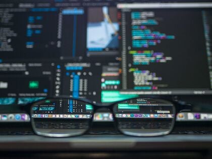 Glasses in front of a screen with lines of code on it